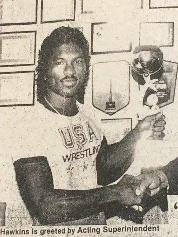 Archive newspaper photo of a USA Wrestling coach holding a trophy