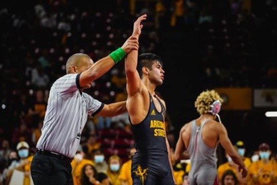 A referee raising the arm of an Arizona State wrestler