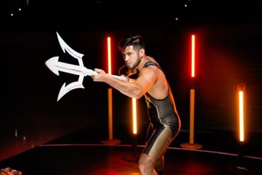 An Arizona State wrestler walking out with a trident under red lights