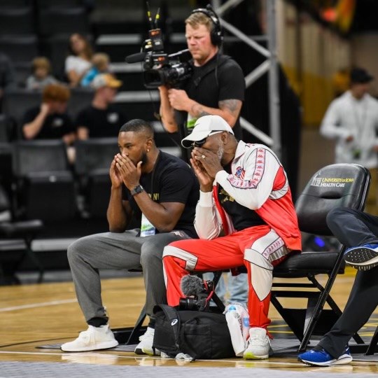 Two coaches sitting courtside with their hands over their faces during a match