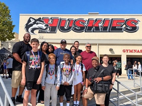 Athletes, coaches and families with medals outside a high school gym
